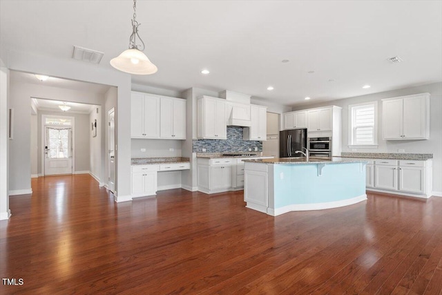 kitchen featuring visible vents, dark wood-style floors, freestanding refrigerator, stainless steel gas stovetop, and a healthy amount of sunlight