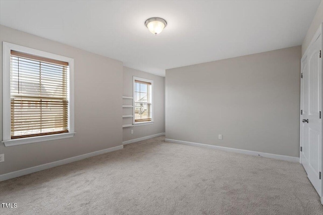 spare room featuring carpet flooring and baseboards