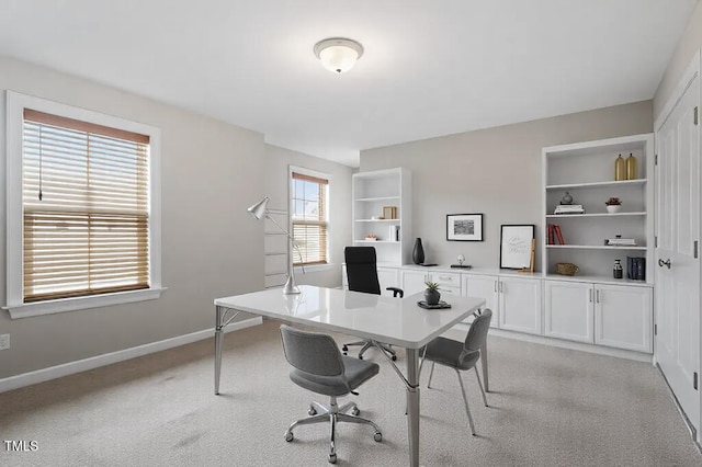 office space with built in features, baseboards, and light carpet