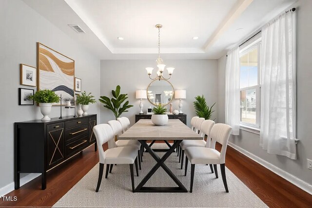 dining area featuring baseboards, visible vents, an inviting chandelier, dark wood-style flooring, and a raised ceiling