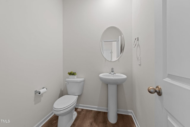 bathroom featuring a sink, toilet, baseboards, and wood finished floors