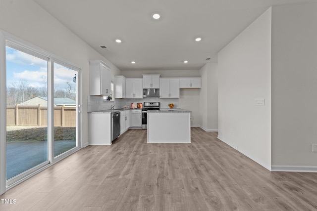 kitchen with light wood finished floors, visible vents, backsplash, stainless steel appliances, and white cabinetry