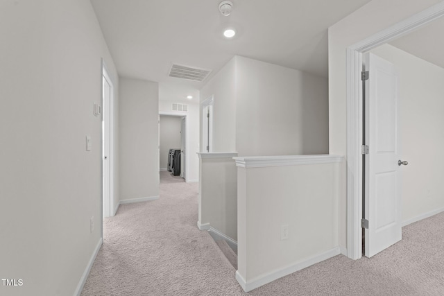 corridor featuring an upstairs landing, visible vents, light colored carpet, and baseboards