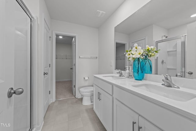 full bathroom featuring a sink, a walk in closet, a stall shower, and double vanity