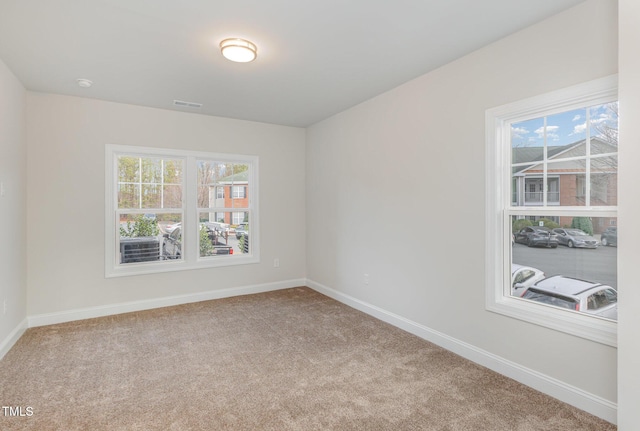 unfurnished room with visible vents, baseboards, and carpet flooring