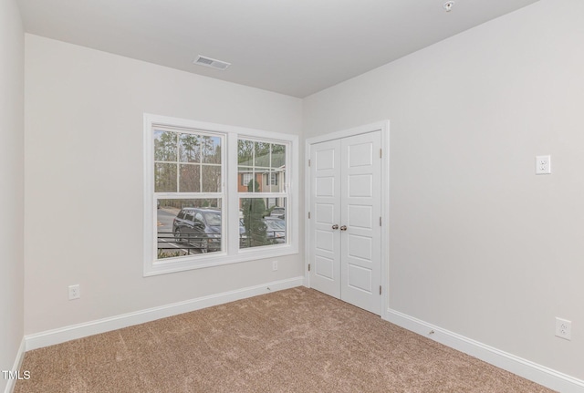 spare room featuring visible vents, carpet floors, and baseboards