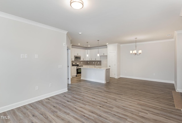 unfurnished living room featuring baseboards, light wood finished floors, an inviting chandelier, recessed lighting, and ornamental molding