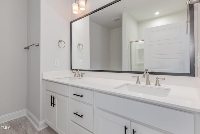 bathroom with double vanity, baseboards, visible vents, and a sink