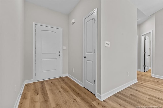 corridor featuring light wood-style flooring and baseboards