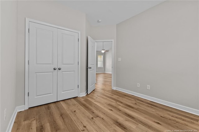 unfurnished bedroom with a closet, baseboards, and light wood finished floors