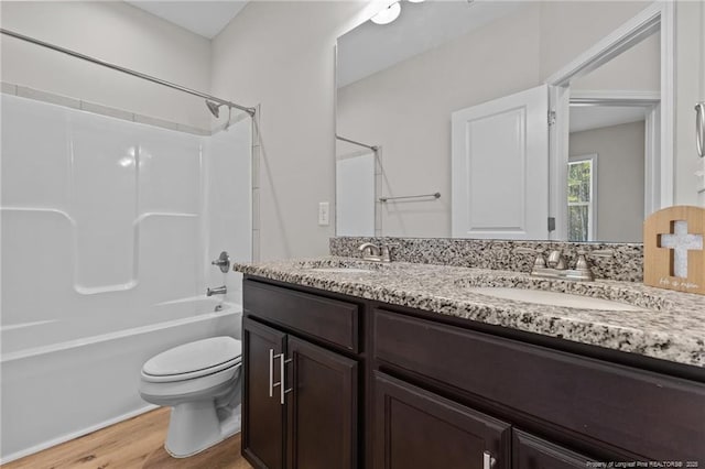 bathroom with double vanity, wood finished floors, toilet, and a sink