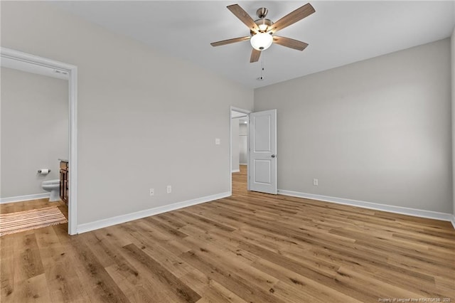 unfurnished bedroom featuring ensuite bath, wood finished floors, baseboards, and ceiling fan