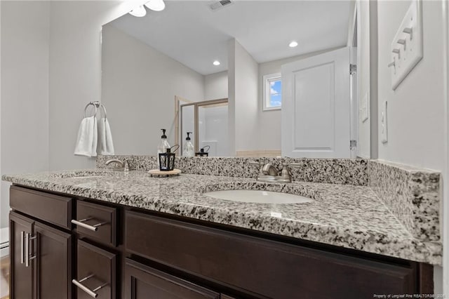 full bath featuring double vanity, visible vents, a stall shower, and a sink