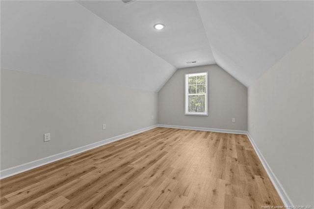 bonus room featuring baseboards, light wood-style floors, and vaulted ceiling