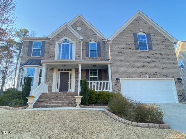 view of front of house with brick siding, covered porch, driveway, and an attached garage