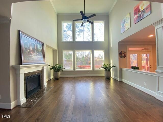 unfurnished living room with a fireplace, crown molding, baseboards, and wood finished floors