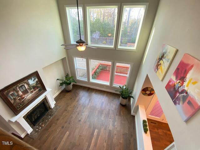 living room featuring a fireplace with flush hearth, baseboards, a ceiling fan, and wood finished floors