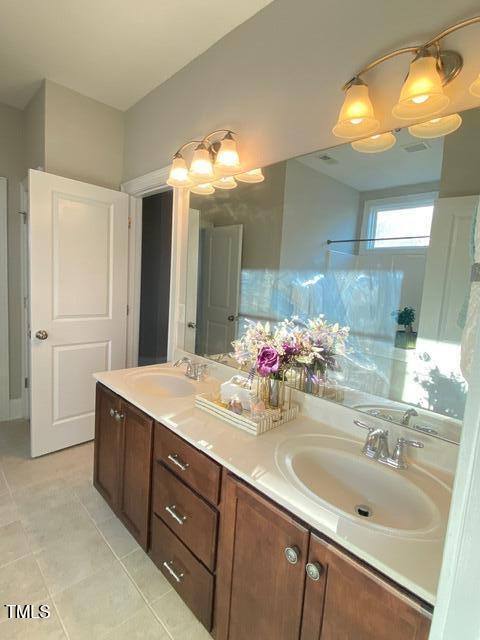 full bath featuring double vanity, tile patterned floors, and a sink