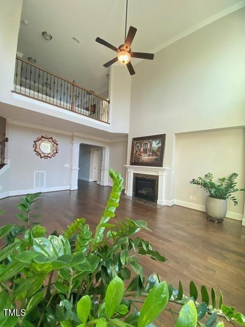 unfurnished living room featuring visible vents, a ceiling fan, a fireplace, baseboards, and a towering ceiling