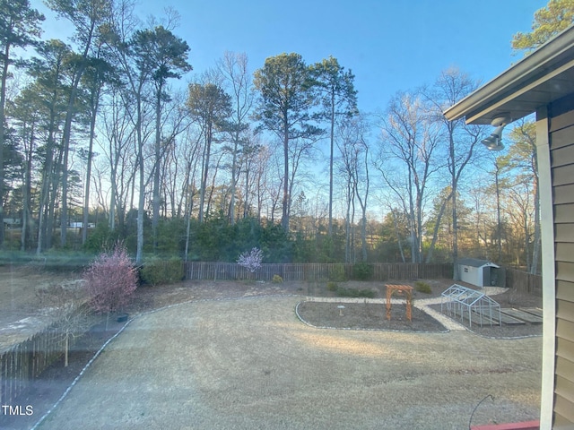 view of yard with an outbuilding, a storage unit, and fence