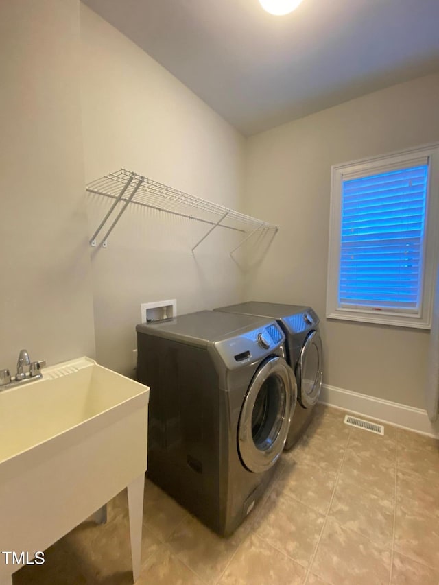 clothes washing area featuring baseboards, visible vents, laundry area, a sink, and washing machine and dryer