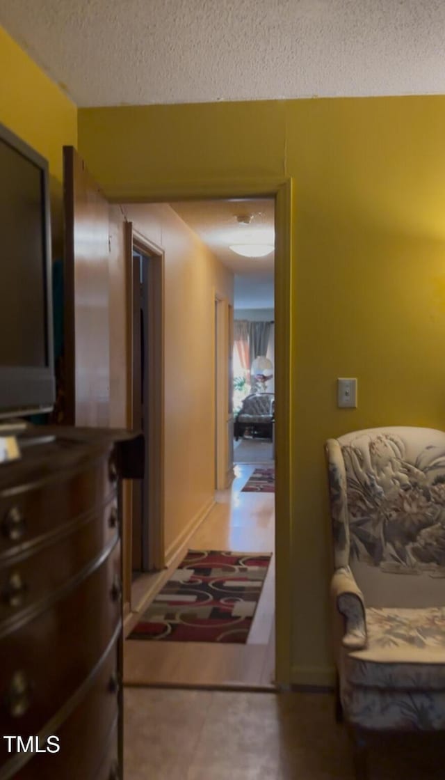 hall featuring baseboards and a textured ceiling