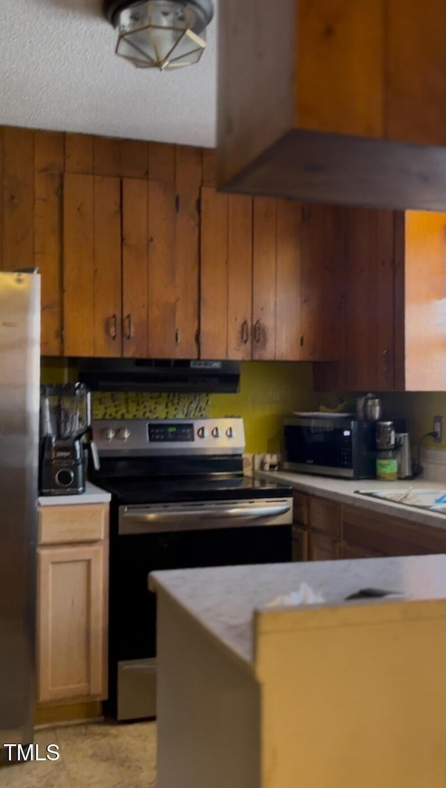 kitchen with under cabinet range hood, stainless steel appliances, wooden walls, and light countertops