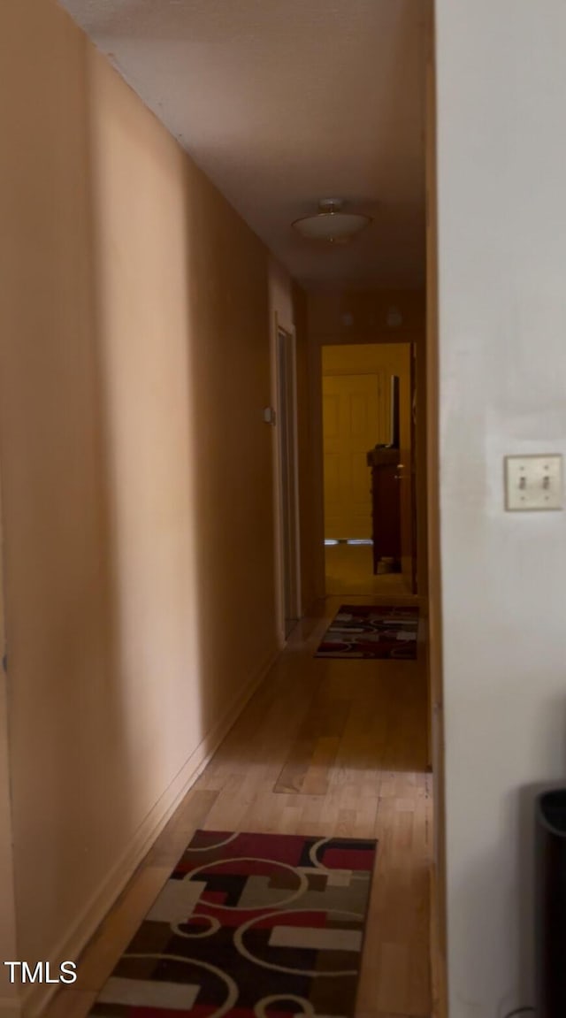 corridor with light wood-style floors and baseboards