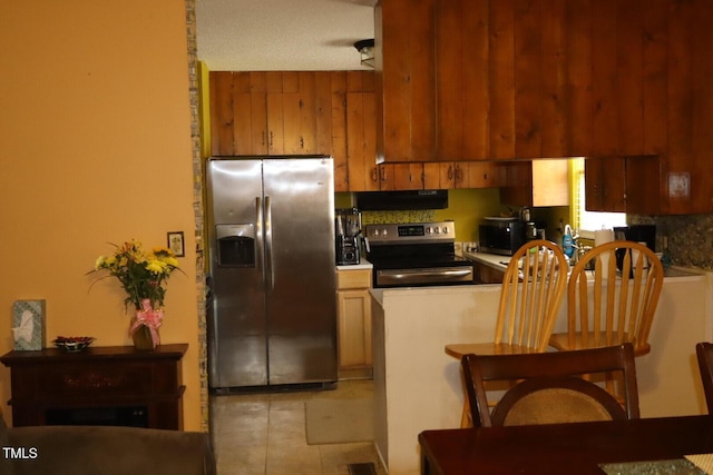 kitchen featuring under cabinet range hood, appliances with stainless steel finishes, and a peninsula