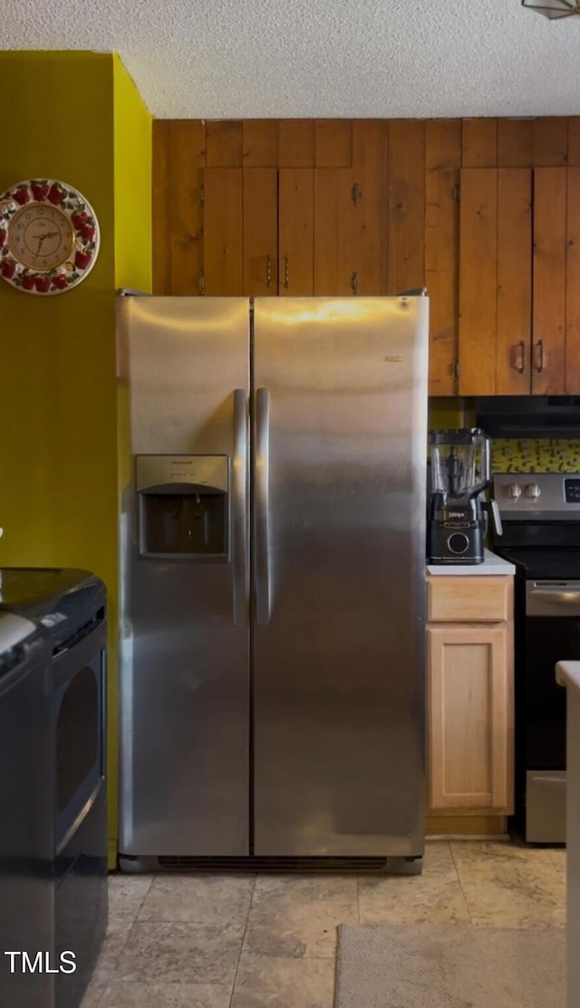 kitchen with a textured ceiling, brown cabinets, under cabinet range hood, and stainless steel appliances