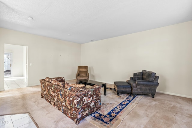 sitting room featuring baseboards, light colored carpet, light tile patterned flooring, and a textured ceiling