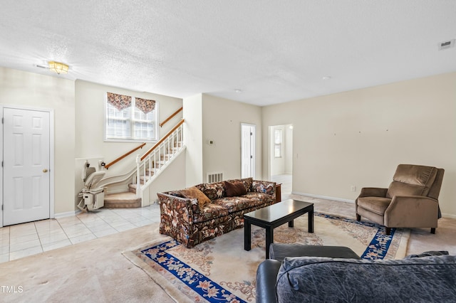 living room featuring visible vents, stairs, carpet flooring, tile patterned floors, and a textured ceiling