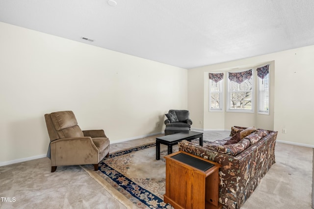 living area with visible vents, baseboards, a textured ceiling, and carpet flooring