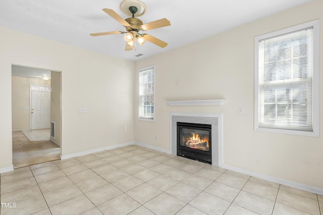 unfurnished living room featuring light tile patterned flooring, a glass covered fireplace, and baseboards