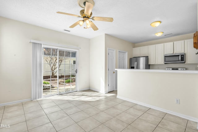 kitchen with visible vents, a textured ceiling, stainless steel appliances, white cabinets, and ceiling fan