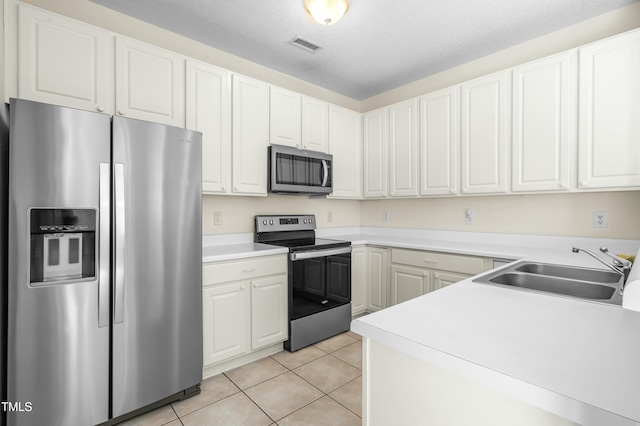 kitchen with a sink, white cabinetry, appliances with stainless steel finishes, light countertops, and light tile patterned floors