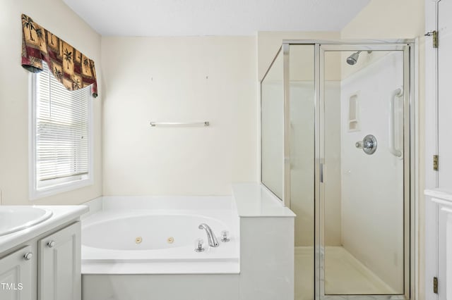 bathroom with a textured ceiling, a tub with jets, a stall shower, and vanity