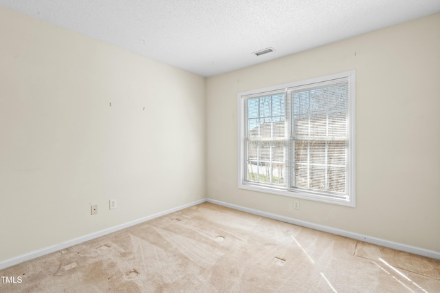 carpeted spare room featuring visible vents, a textured ceiling, and baseboards