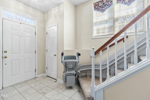 tiled entryway featuring baseboards and stairs