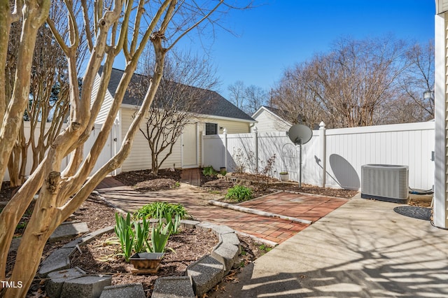 rear view of property featuring roof with shingles, central AC unit, a fenced backyard, and a patio area