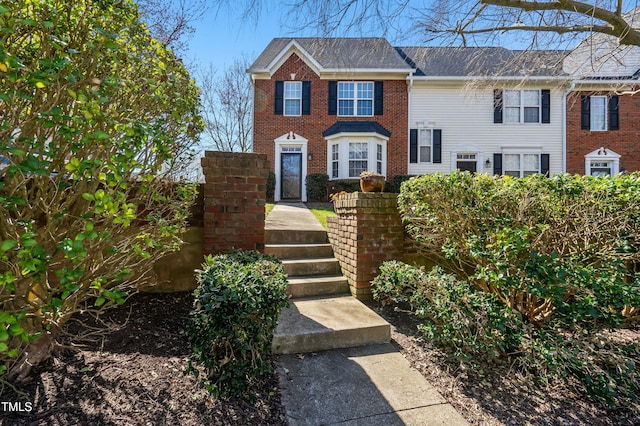 view of front of house with brick siding and roof with shingles