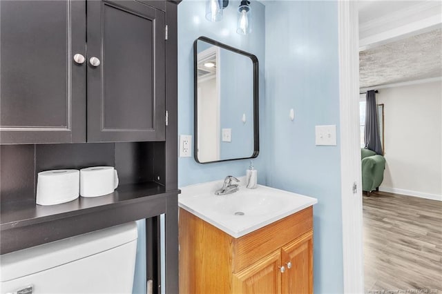 bathroom featuring a textured ceiling, vanity, baseboards, and wood finished floors