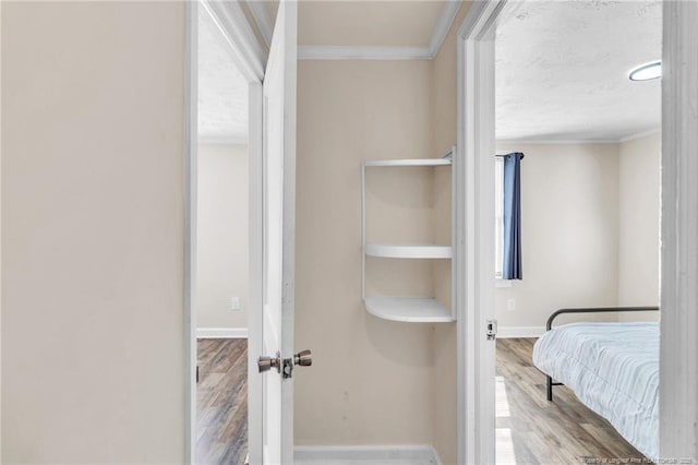 interior space featuring wood finished floors, baseboards, and ornamental molding