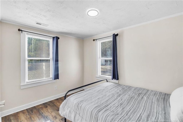 bedroom with visible vents, multiple windows, baseboards, and wood finished floors