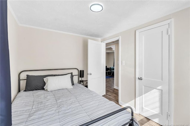 bedroom featuring baseboards, wood finished floors, and crown molding