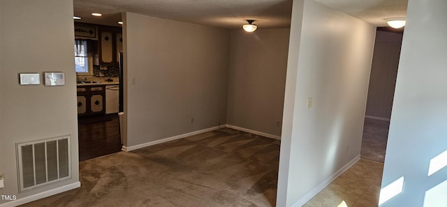 spare room with a sink, visible vents, baseboards, and carpet