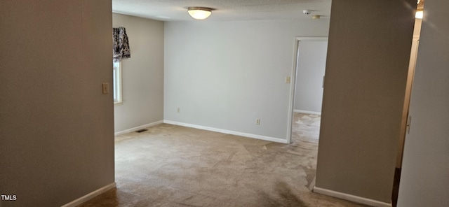 carpeted empty room featuring baseboards