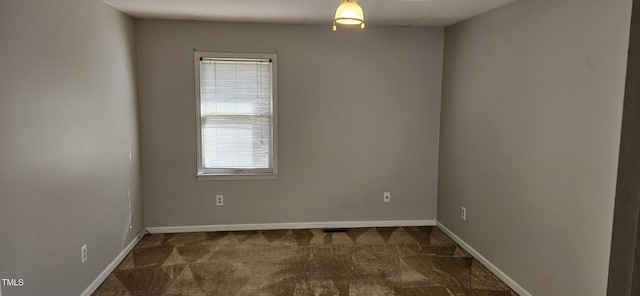 unfurnished room featuring baseboards and dark colored carpet