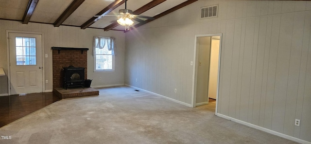 unfurnished living room featuring carpet, visible vents, lofted ceiling with beams, a wood stove, and ceiling fan