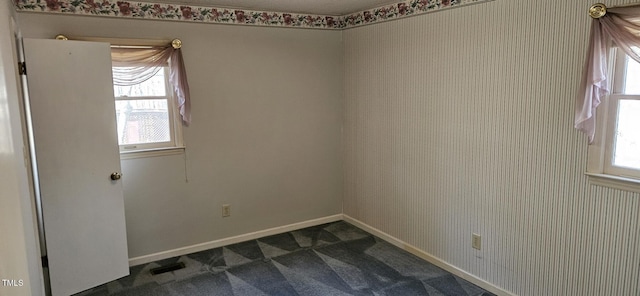 unfurnished room with visible vents, dark carpet, wallpapered walls, and baseboards